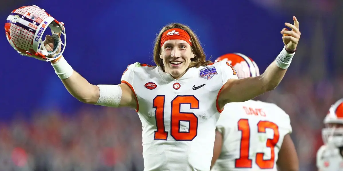 trevor lawrence raising his arms in a clemson uniform.